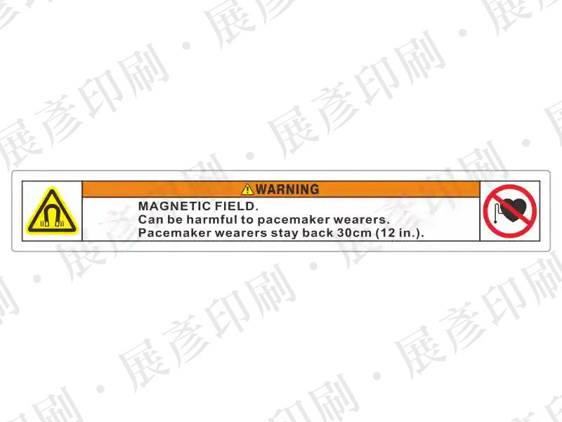 左側磁場警告三角,右側禁止心律調節器圖示,中間橘底「WARNING」,文字「MAGNETIC FIELD. Can be harmful to pacemaker wearers stay back 30cm (12 in.).」。用途:長條形強磁場警示。語系:英文