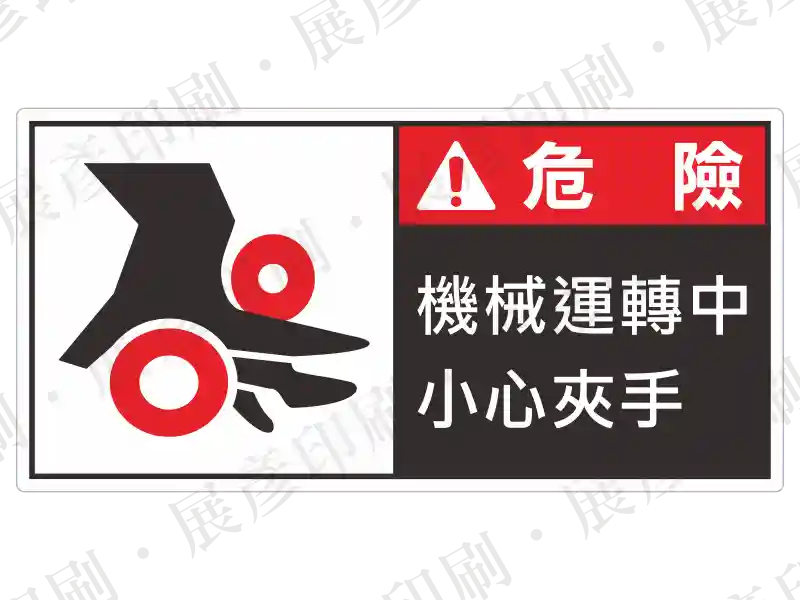 左側為兩個滾輪中間夾手的圖示,右側紅色區塊寫白字「危 險」,黑色區塊寫白字「機械運轉中 小心夾手」。用途:滾輪機械運轉危險警示。語系:繁中