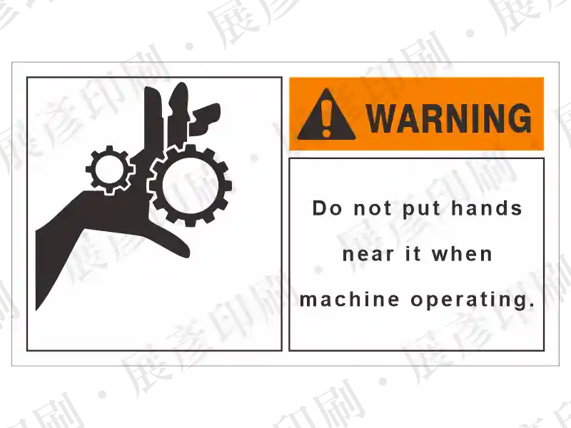 左側齒輪夾手圖示,右側橘底「WARNING」,文字「Do not put hands near it when machine operating.」。用途:機械運作禁止伸手警示。語系:英文