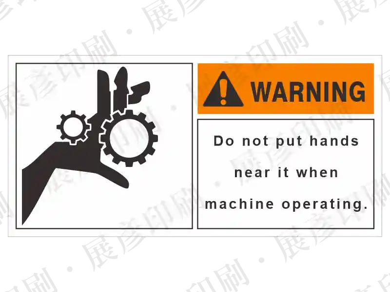 左側齒輪夾手圖示,右側橘底「WARNING」,文字「Do not put hands near it when machine operating.」。用途:機械運作禁止伸手警示。語系:英文
