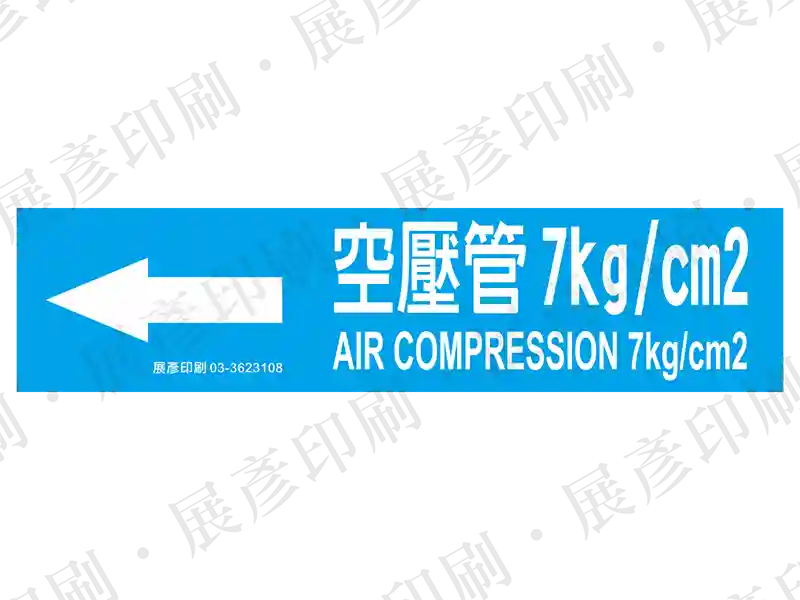 藍底白字，左側箭頭，文字「空壓管 7kg/cm2 AIR COMPRESSION 7kg/cm2」。用途：空壓管路標示流向。語系：繁中/英文