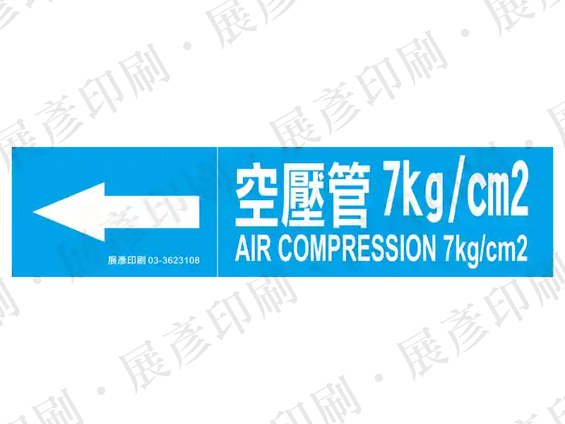 藍底白字,左側箭頭,文字「空壓管 7kg/cm2 AIR COMPRESSION 7kg/cm2」。用途:空壓管路標示流向。語系:繁中/英文