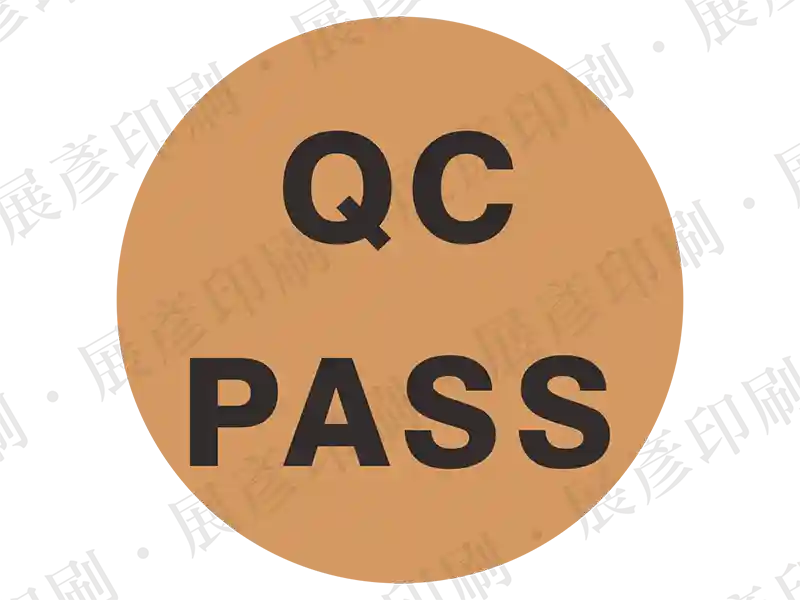 古銅色/褐色底黑字，文字「QC PASS」。用途：品管通過標示。語系：英文